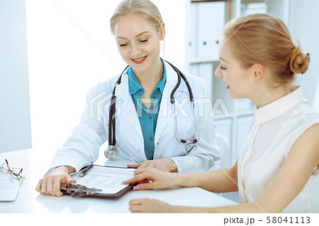 Doctor and patient talking in hospital office while sitting at the desk. Health care and client 58041113