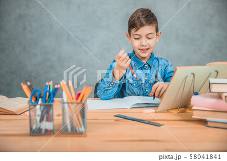 Learning process. Boy in casual clothes holding two pens, red and black, thinking what to write. 58041841