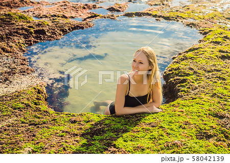 Young woman tourist on Pantai Tegal Wangi Beach sitting in a bath of sea water, Bali Island 58042139