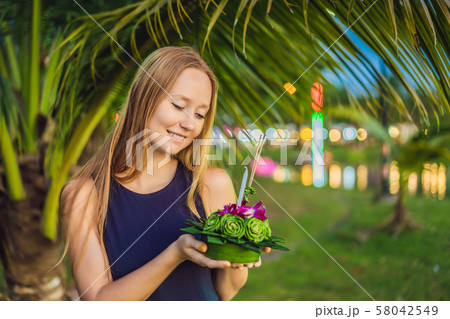 A female tourist holds the Loy Krathong in her hands and is about to launch it into the water. Loy A female tourist holds the Loy Krathong in her hands and is about to launch it into the water. Loy 58042549