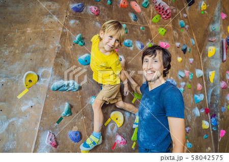 Dad and son at the climbing wall. Family sport, healthy lifestyle, happy family Dad and son at the climbing wall. Family sport, healthy lifestyle, happy family 58042575