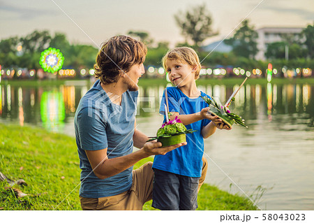 father and son tourists holds the Loy Krathong in her hands and is about to launch it into the water father and son tourists holds the Loy Krathong in her hands and is about to launch it into the water 58043023
