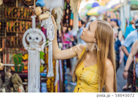 Woman traveler choose souvenirs in the market at Ubud in Bali, Indonesia Woman traveler choose souvenirs in the market at Ubud in Bali, Indonesia 58043072