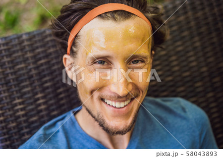 Young handsome man makes a green cosmetic face mask. Skin Care for Men Concept 58043893