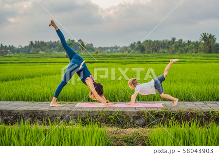 Boy and his yoga teacher doing yoga in a rice field 58043903