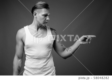 Studio shot of muscular man shot in black and white Studio shot of muscular man shot in black and white 58048282
