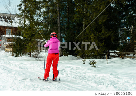 A woman is skiing and climbing up the hill to go 58055106