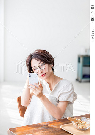 スマホを見ながら朝食を食べる女性 スマホを見ながら朝食を食べる女性 58057083