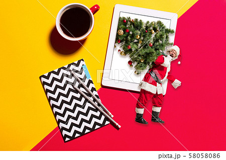 Happy Christmas Santa Claus carrying a Christmas tree from tablet's screen 58058086