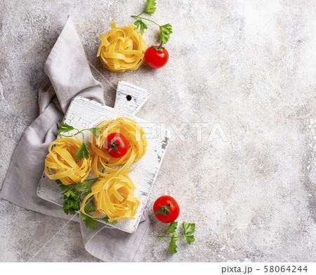 Raw pasta tagliatelle or fettuccine 58064244