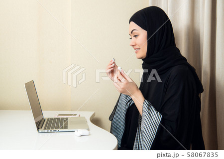 Close-up photos of hijab women listening to music using modern wireless ear phones facing the camera Close-up photos of hijab women listening to music using modern wireless ear phones facing the camera 58067835