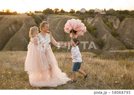 Stylish young boy gives a big flower to his mom in 58068795