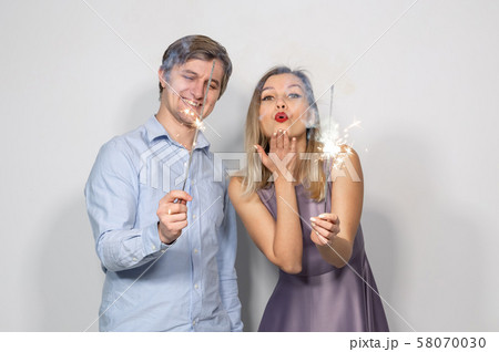 Party, new year, christmas and holidays concept - young couple holding sparklers on white background 58070030