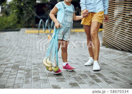 Girl carrying mesh shopping bag stock photo Girl carrying mesh shopping bag stock photo 58070334