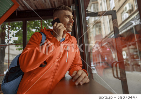 Pleased young man talking on the smartphone indoors Pleased young man talking on the smartphone indoors 58070447