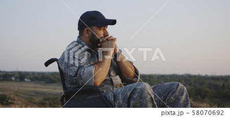 Wheelchaired soldier looking away into distance Wheelchaired soldier looking away into distance 58070692