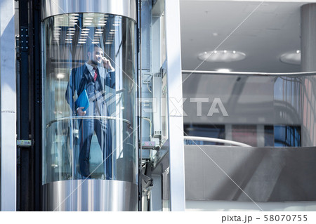 Businessman in elevator talking by phone 58070755