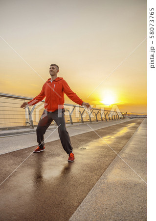 Contented young man warming up on a bridge Contented young man warming up on a bridge 58073765