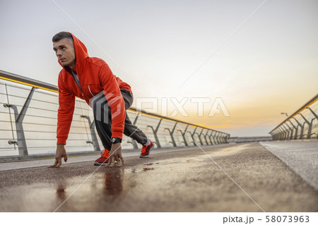Concentrated male athlete standing on a bridge Concentrated male athlete standing on a bridge 58073963