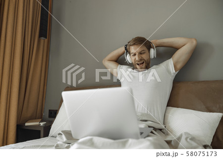 Young man watching a movie in his bed 58075173