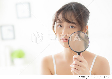 Beautiful young asian woman with magnifying of skin a problem of acne 58076135
