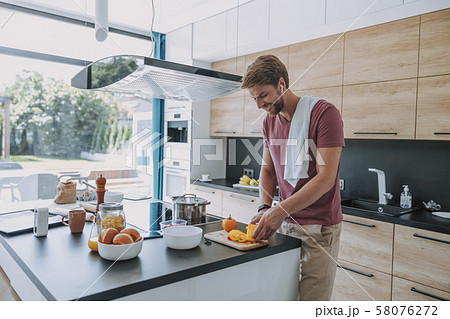 Smiling cook preparing food and listening to music Smiling cook preparing food and listening to music 58076272