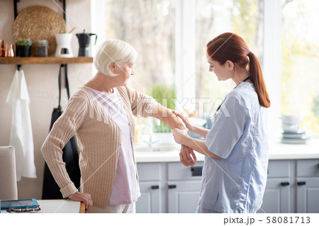 Caring red-haired nurse putting gel on arm for woman 58081713