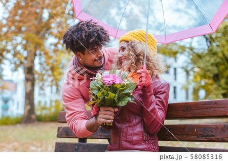 Man surprising his wife with a bouquet of flowers on a drizzly fall day 58085316