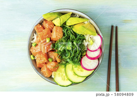 Salmon poke with avocado, wakame and cucumber, shot from the top on a teal blue background with 58094809
