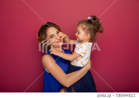Daughter and mother isolated in a pink studio together. Daughter and mother isolated in a pink studio together. 58094822