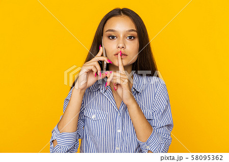 Woman talking phone and showing to keep silence sign. 58095362