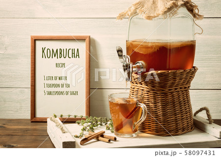 Fresh homemade kombucha fermented tea drink in a jar with faucet and in a cup on a white tray, the Fresh homemade kombucha fermented tea drink in a jar with faucet and in a cup on a white tray, the 58097431
