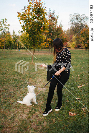 Mother and little daughter walking with her dog in autumn weather. Stylish little daughter and her 58097492
