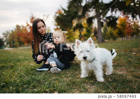 Happy mother and her daughter playing with dog in autumn park. Family, pet, domestic animal and 58097493
