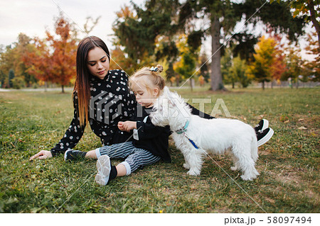 Happy mother and her daughter playing with dog in autumn park. Family, pet, domestic animal and Happy mother and her daughter playing with dog in autumn park. Family, pet, domestic animal and 58097494