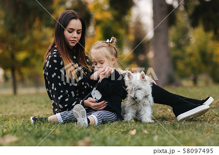 Happy mother and her daughter playing with dog in autumn park. Family, pet, domestic animal and 58097495