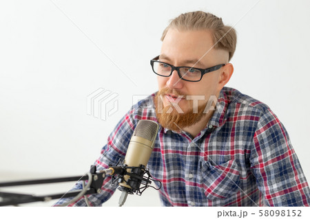 Radio, DJ, blogging and people concept - Close-up of man sitting in front of microphone, host at 58098152