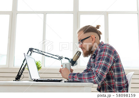 Blogger, streamer and people concept - Funny young man DJ working on the radio Blogger, streamer and people concept - Funny young man DJ working on the radio 58098159