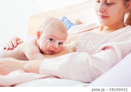 Newborn and mother in relaxed laid back breastfeeding pose 58100422