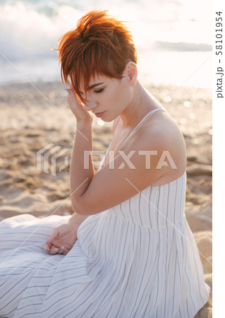 Woman relaxing on beach at sunset. 58101954