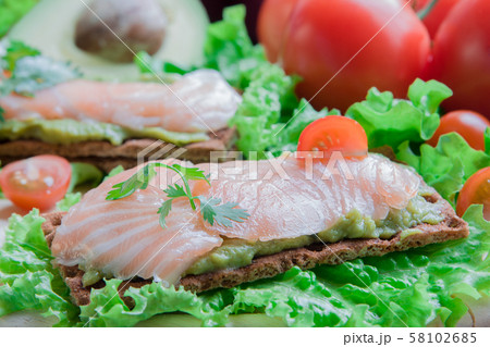 Crispbread with guacamole and salmon on vegetable background 58102685