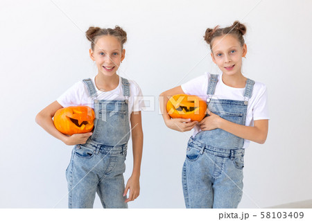 Happy Halloween, holidays and childhood concept - Cute little twins sisters girls with a pumpkins 58103409