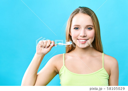 portrait of attractive caucasian smiling woman isolated on blue studio shot brushing her teeth 58105029