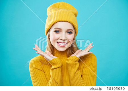 Portrait of a beautiful girl, in a yellow hat and sweater, looking at the camera and smiling cute. 58105030