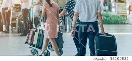 Passengers with big roller luggage stand to wait for the car to pick up at airport arrival terminal. 58109883