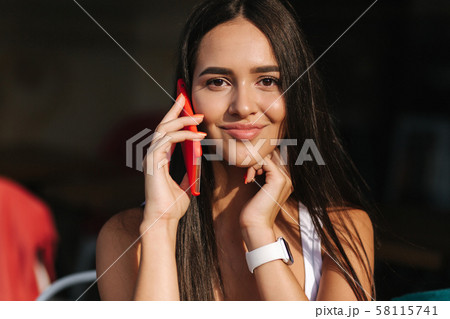 Beautiful brunette female talking on the phone in the cafe. Close ou of woman using phone Beautiful brunette female talking on the phone in the cafe. Close ou of woman using phone 58115741