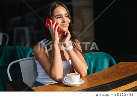 Beautiful brunette female talking on the phone in the cafe. Close ou of woman using phone 58115742