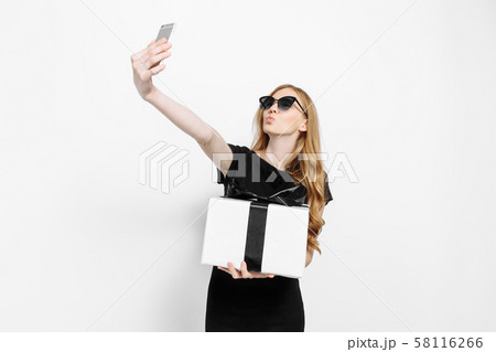 Happy elegant young girl in a black dress, holding Happy elegant young girl in a black dress, holding 58116266