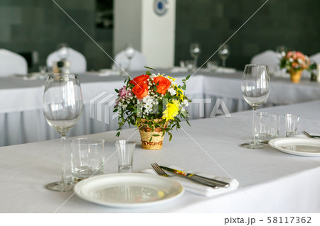 A closeup of restaurant table set with colourful flower bouquet in wicker wase A closeup of restaurant table set with colourful flower bouquet in wicker wase 58117362