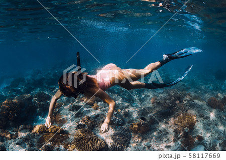 Woman freediver with fins underwater. Freediving in blue ocean Woman freediver with fins underwater. Freediving in blue ocean 58117669